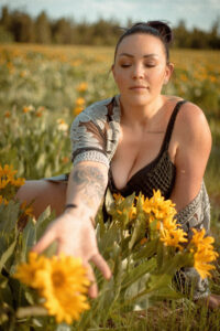 A young woman reaches for a flower