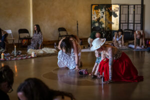 A group of people kneel in prayer at a plant medicine ceremony
